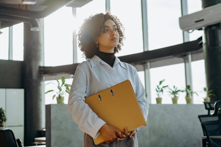 A thoughtful tech professional looking out a modern office window, symbolizing the emotional complexity and signs of a career change from Google into a new chapter. Signs You Need A Career Change.
