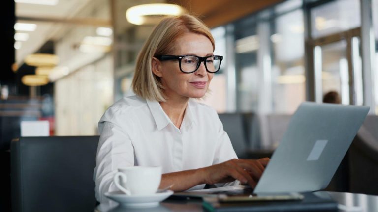Female professional working on a laptop in a modern office, representing a midlife career transition for product managers.
