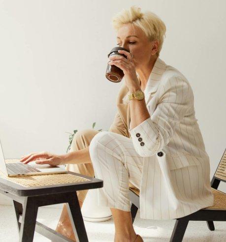 Professional woman over 40 drinking coffee at laptop — career coach for women over 40